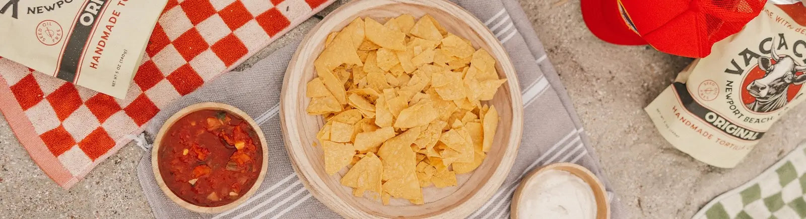 Bowl of tortilla chips with salsa and a checkered napkin on a table