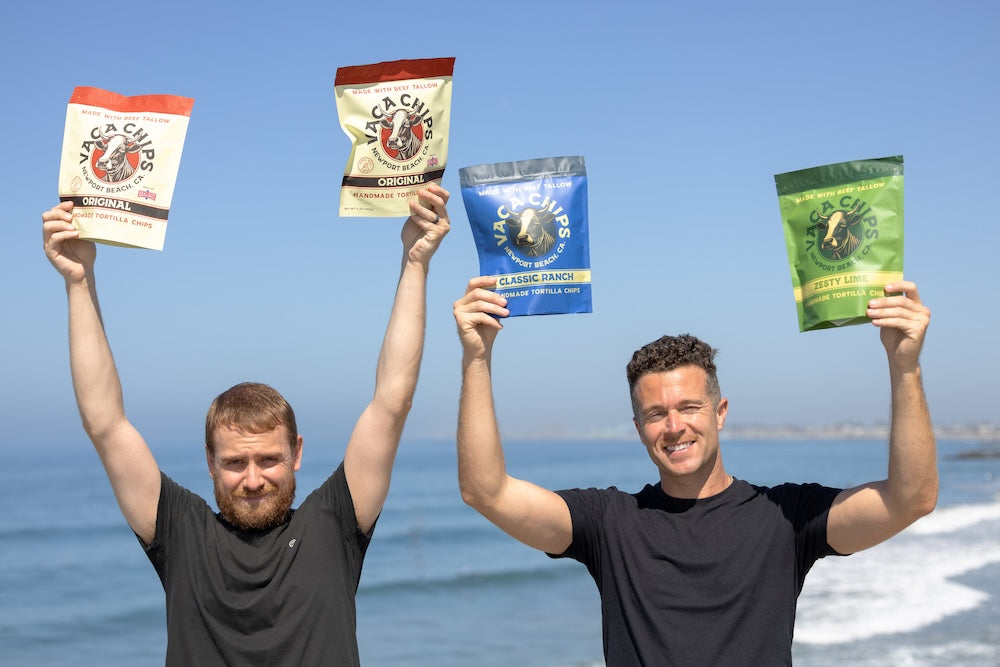 Josh Haddox and Brian Gibb holding bags of vaca chips on the beach